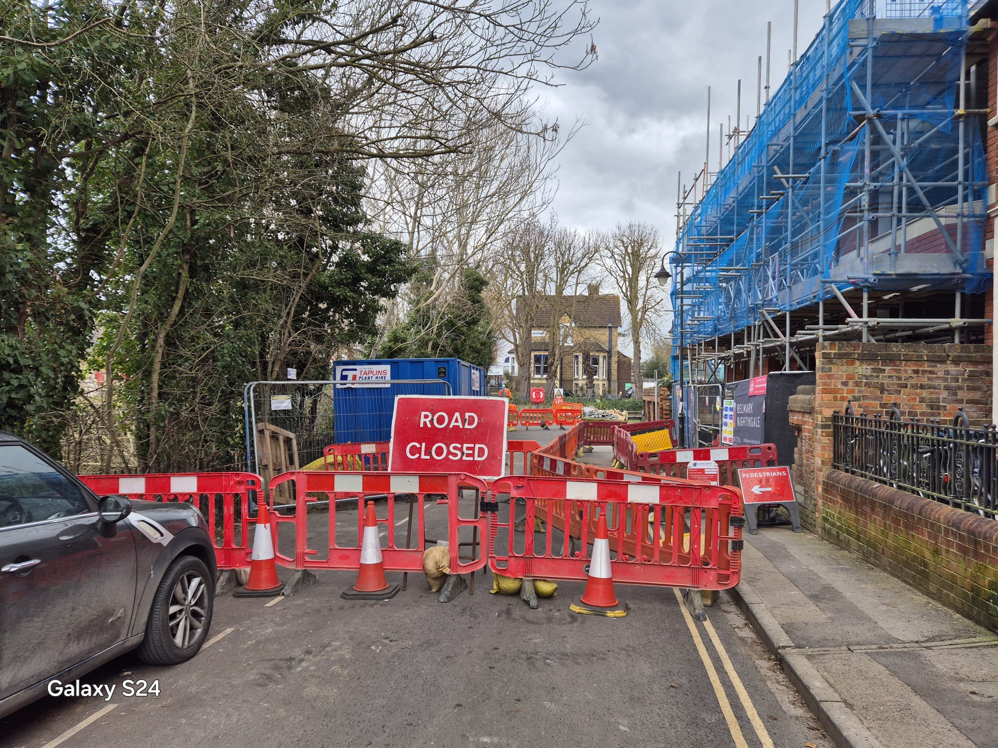 Road closure barriers in front of a scaffolded building on a town street