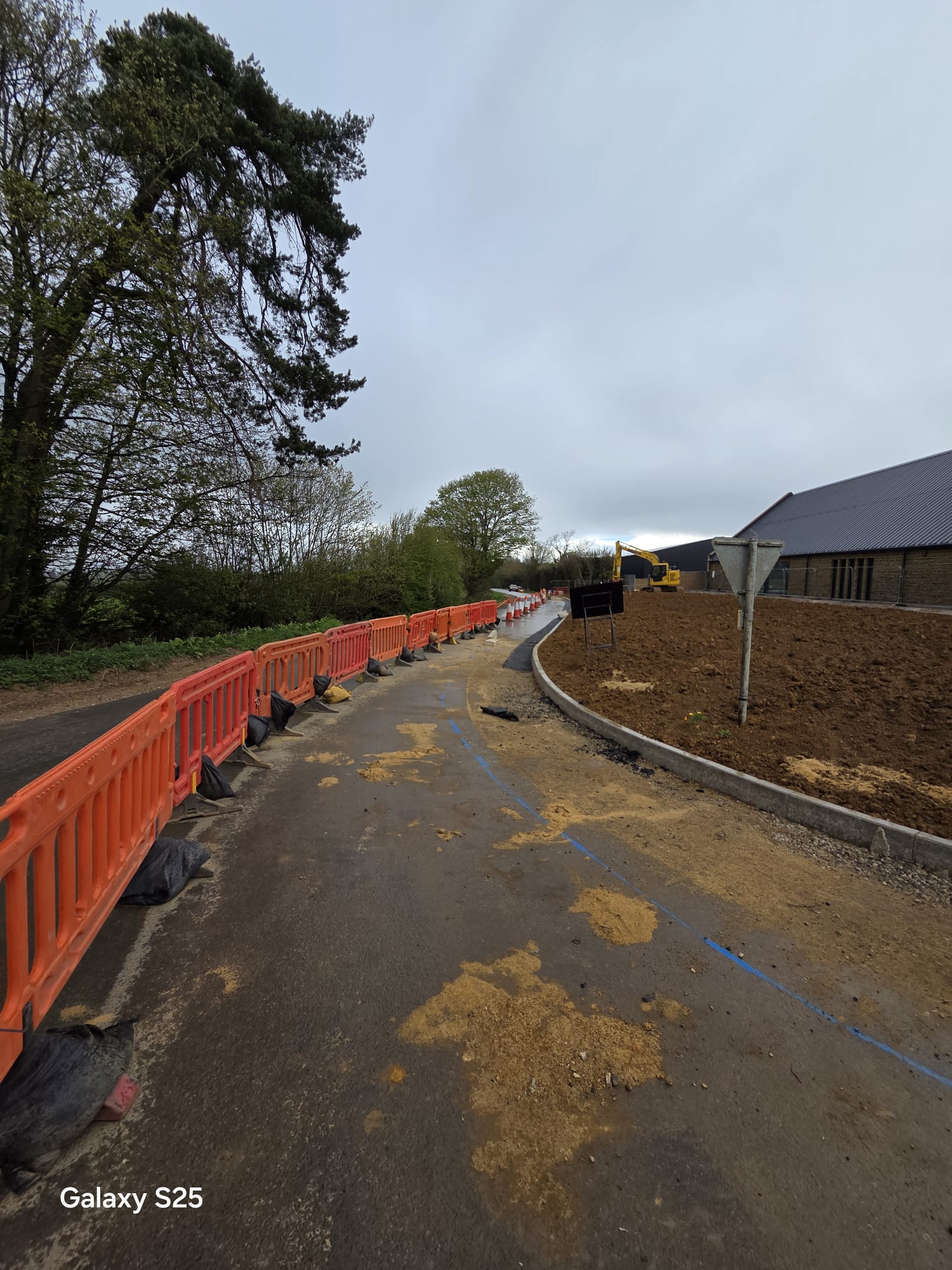 Barrier run guiding traffic past plant working on a construction site access road
