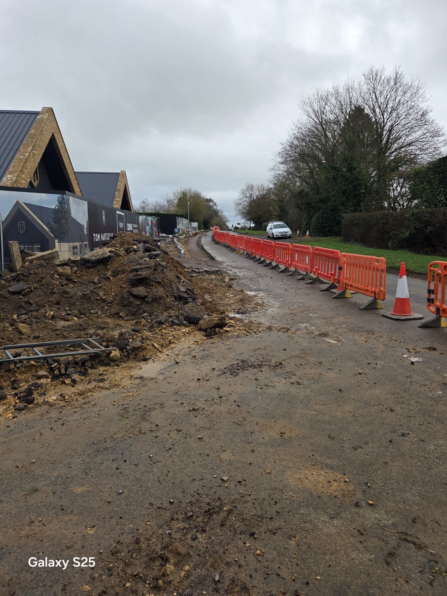 Excavated ground behind traffic management barriers and cones on a construction site access