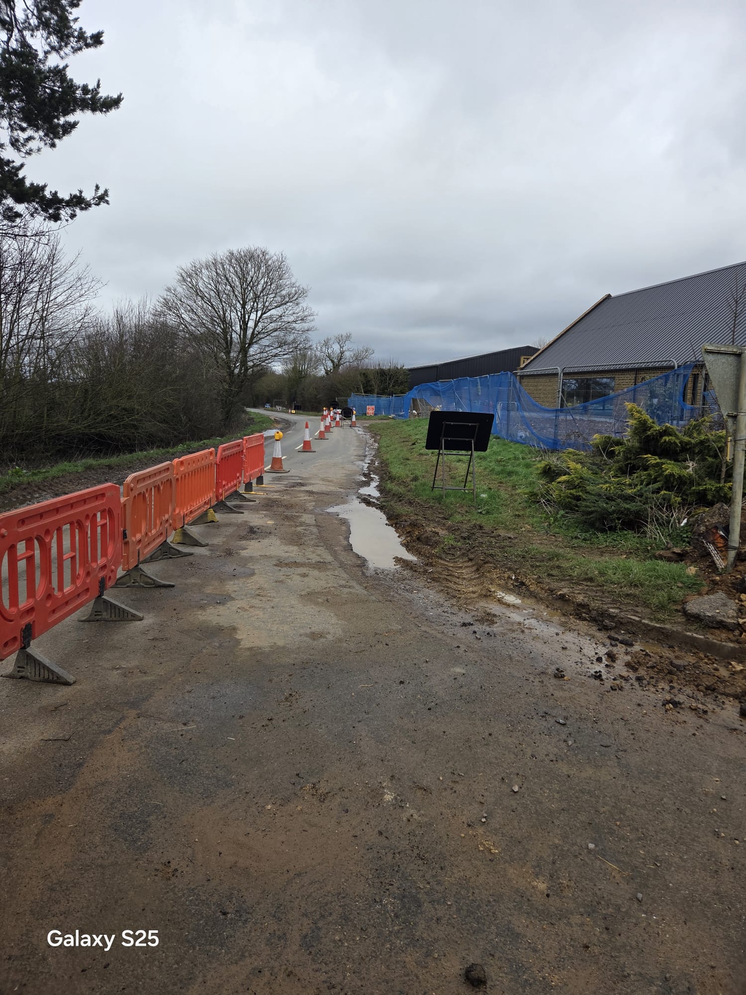 Barrier line and site fencing guarding an unmade road edge on a construction traffic management scheme