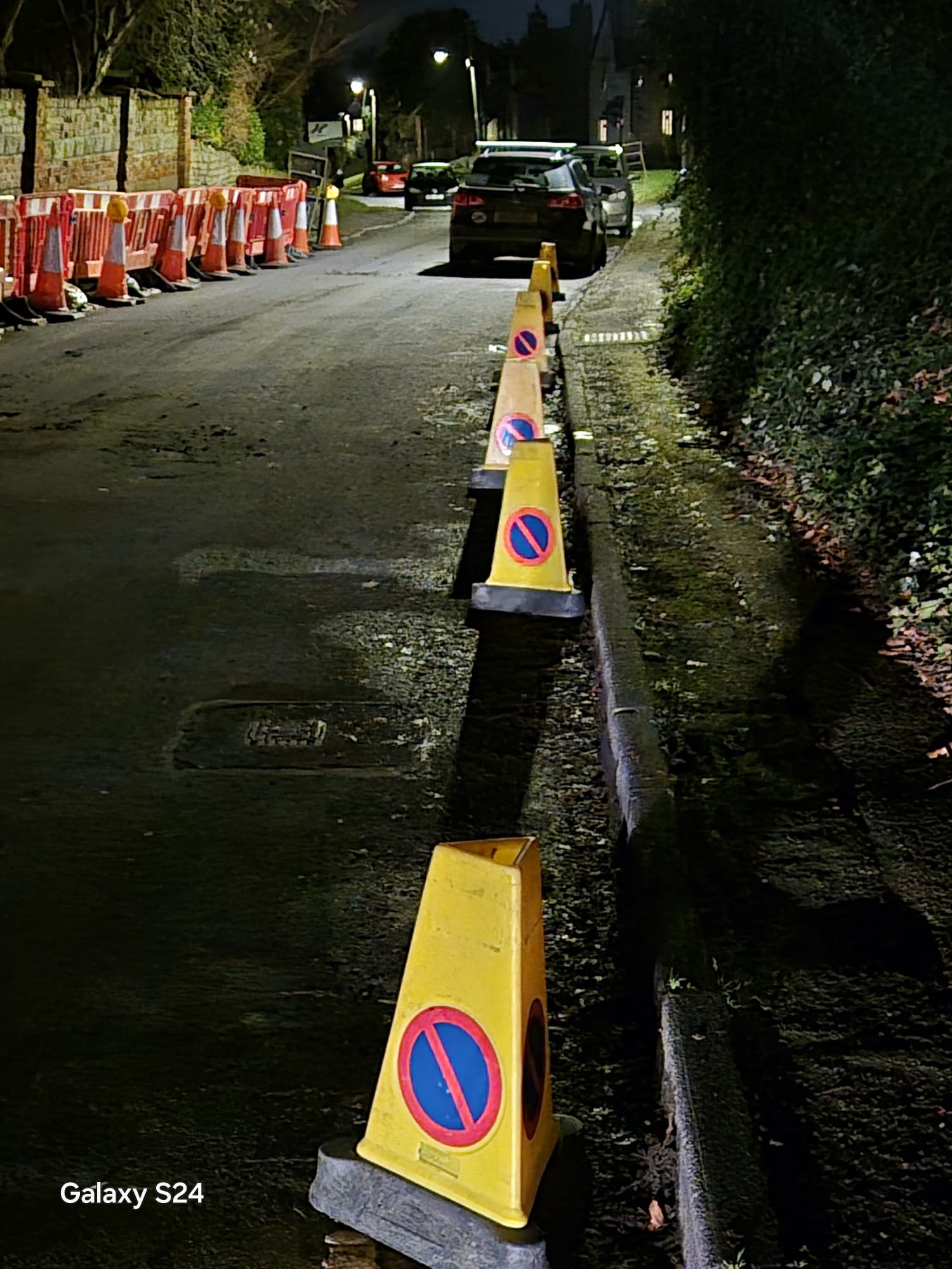 No waiting cones setting out a parking suspension along a kerb line at night