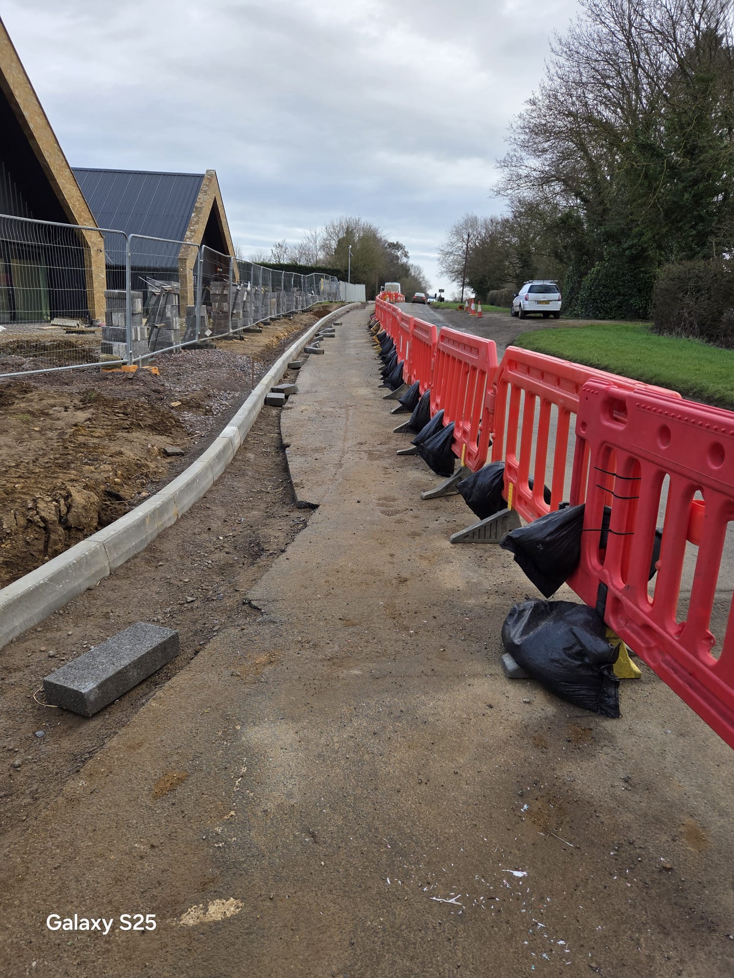Temporary pedestrian walkway formed with barriers and ballast beside a work site