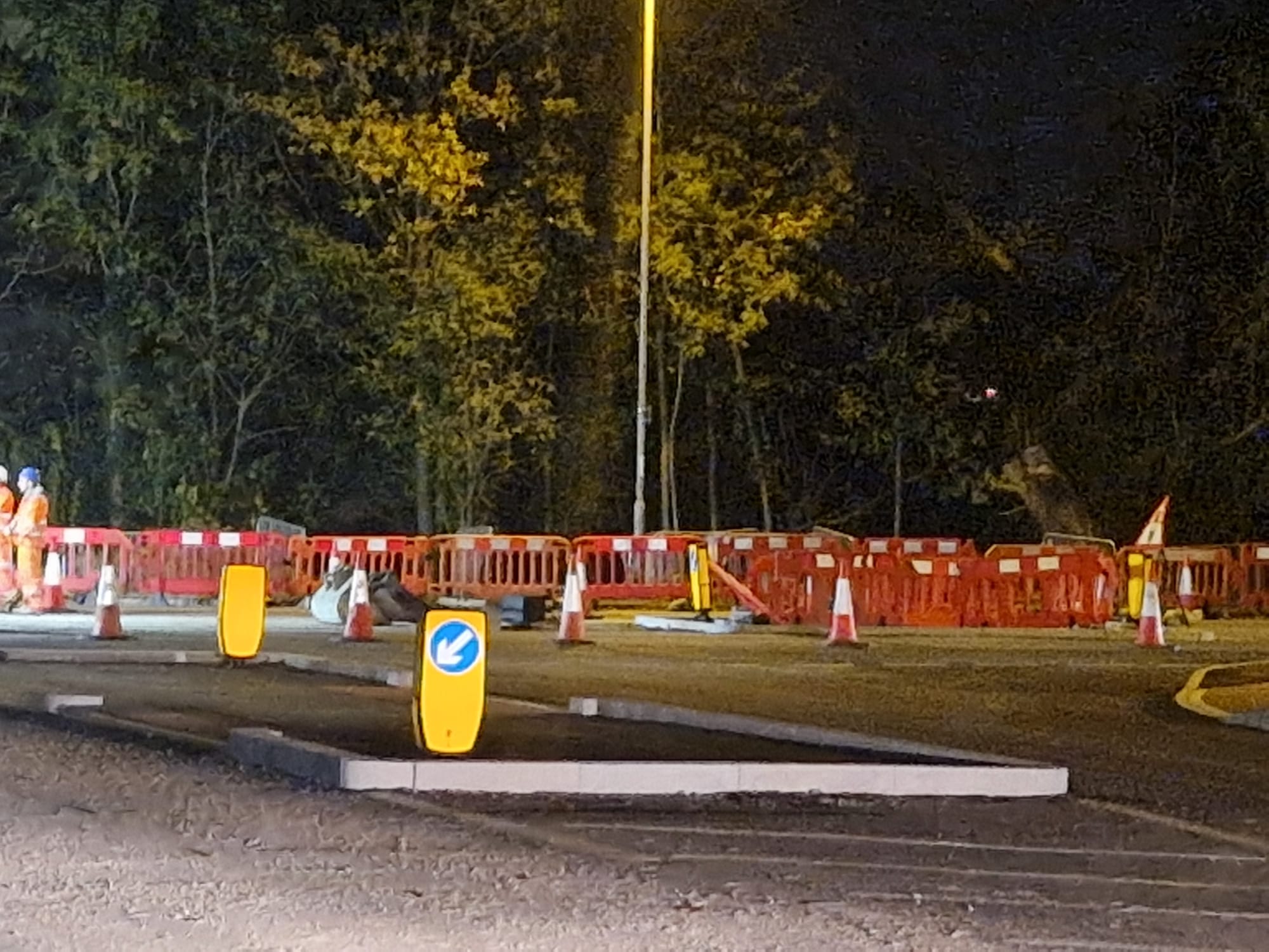 Night works site enclosed by barriers with a lit arrow bollard