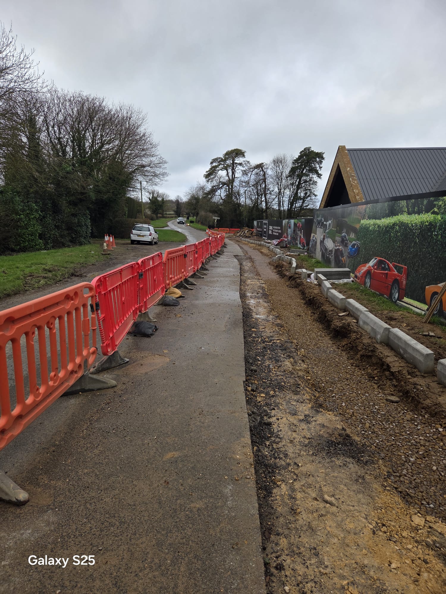 Temporary walkway protected by barriers next to an excavated road shoulder