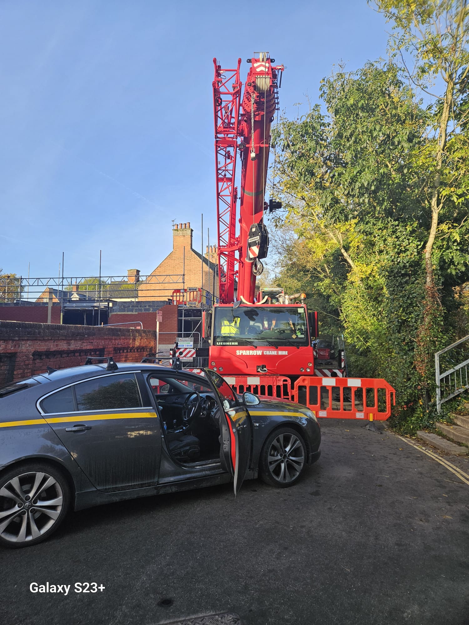 Mobile crane set up on a residential street behind traffic management barriers