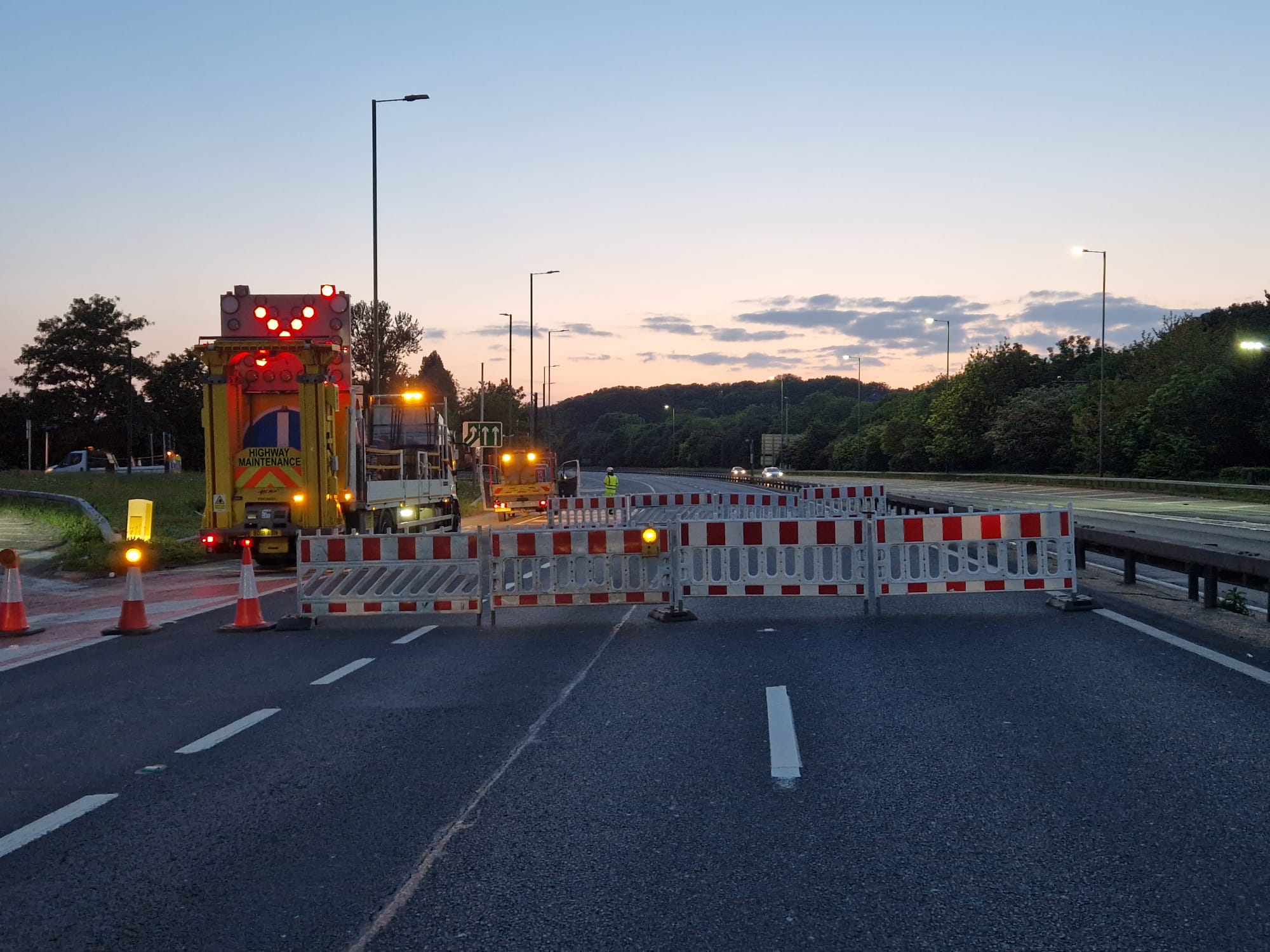 Barriers and works vehicle closing a motorway lane at night