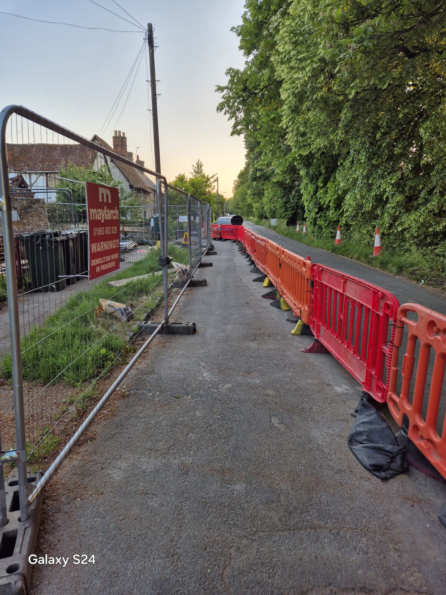 Fenced pedestrian diversion route at dusk near a residential area