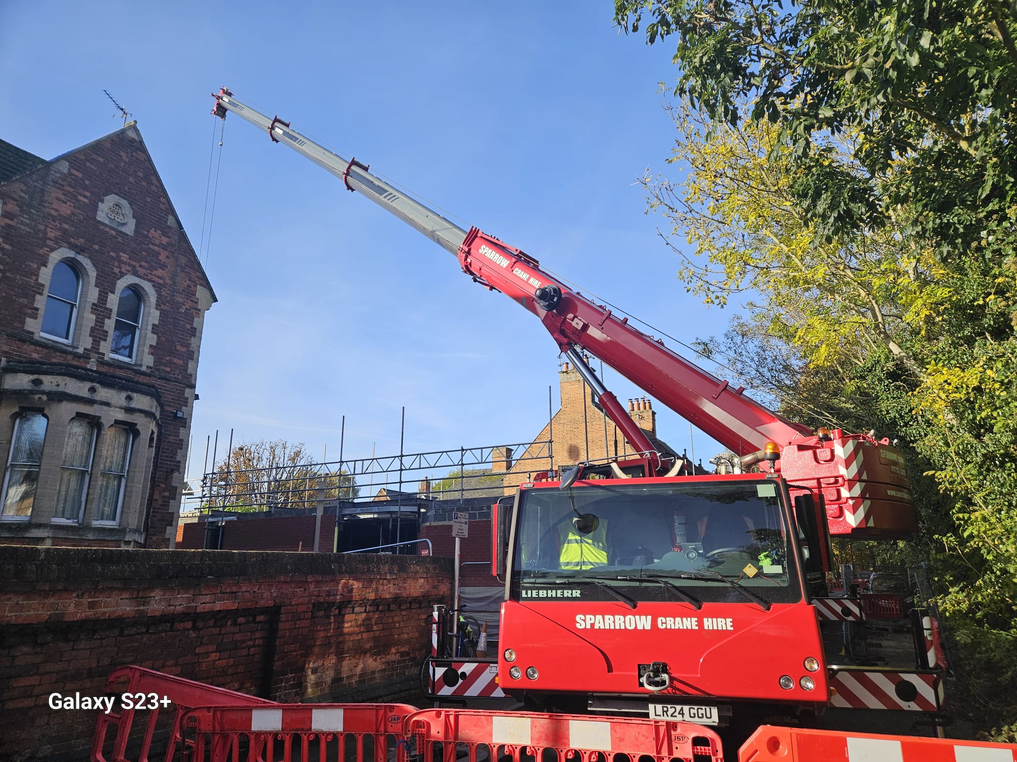 Mobile crane lifting from a street kept clear by traffic management barriers