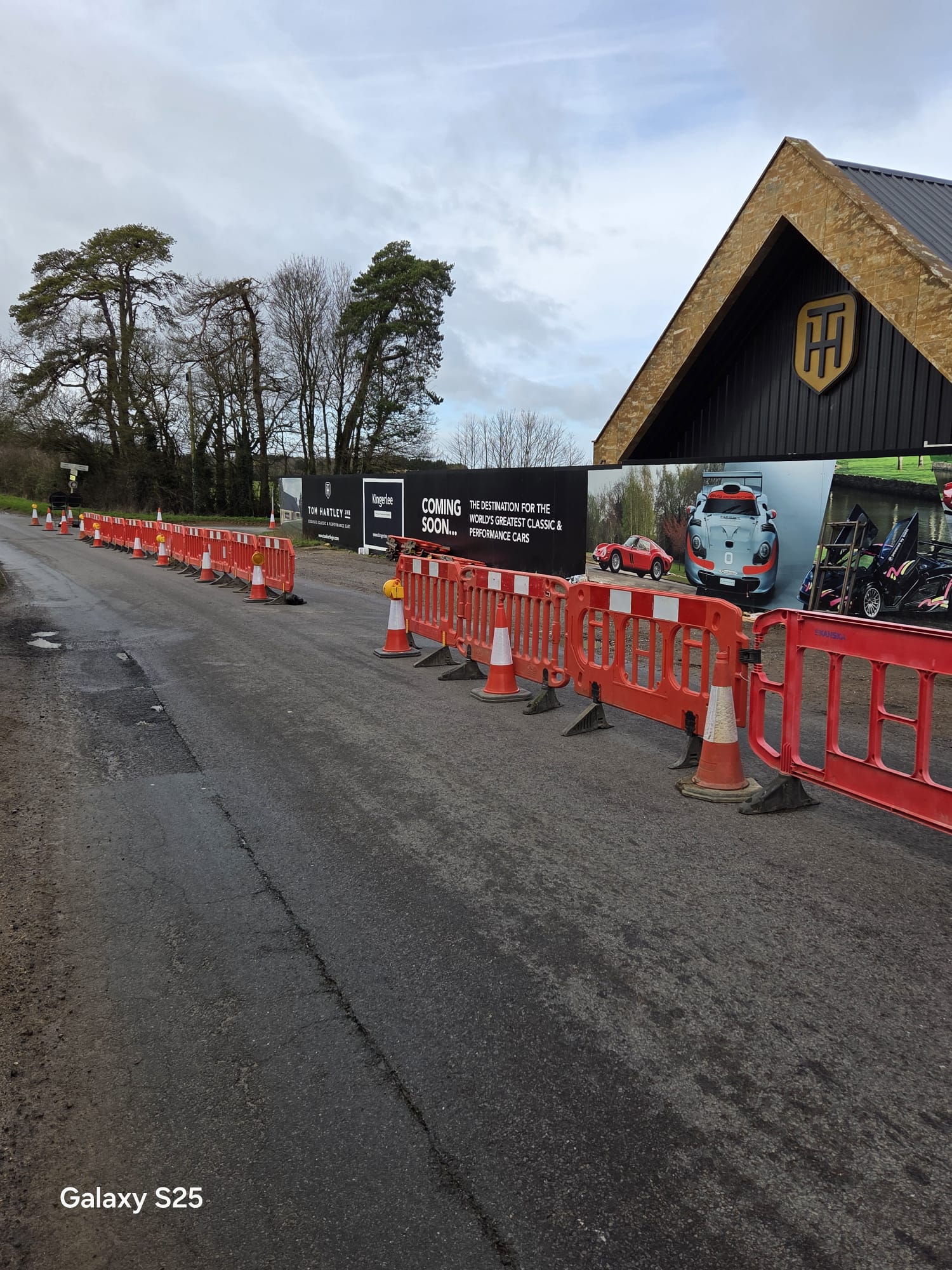 Barriers and cones set out along a public road in front of construction hoarding
