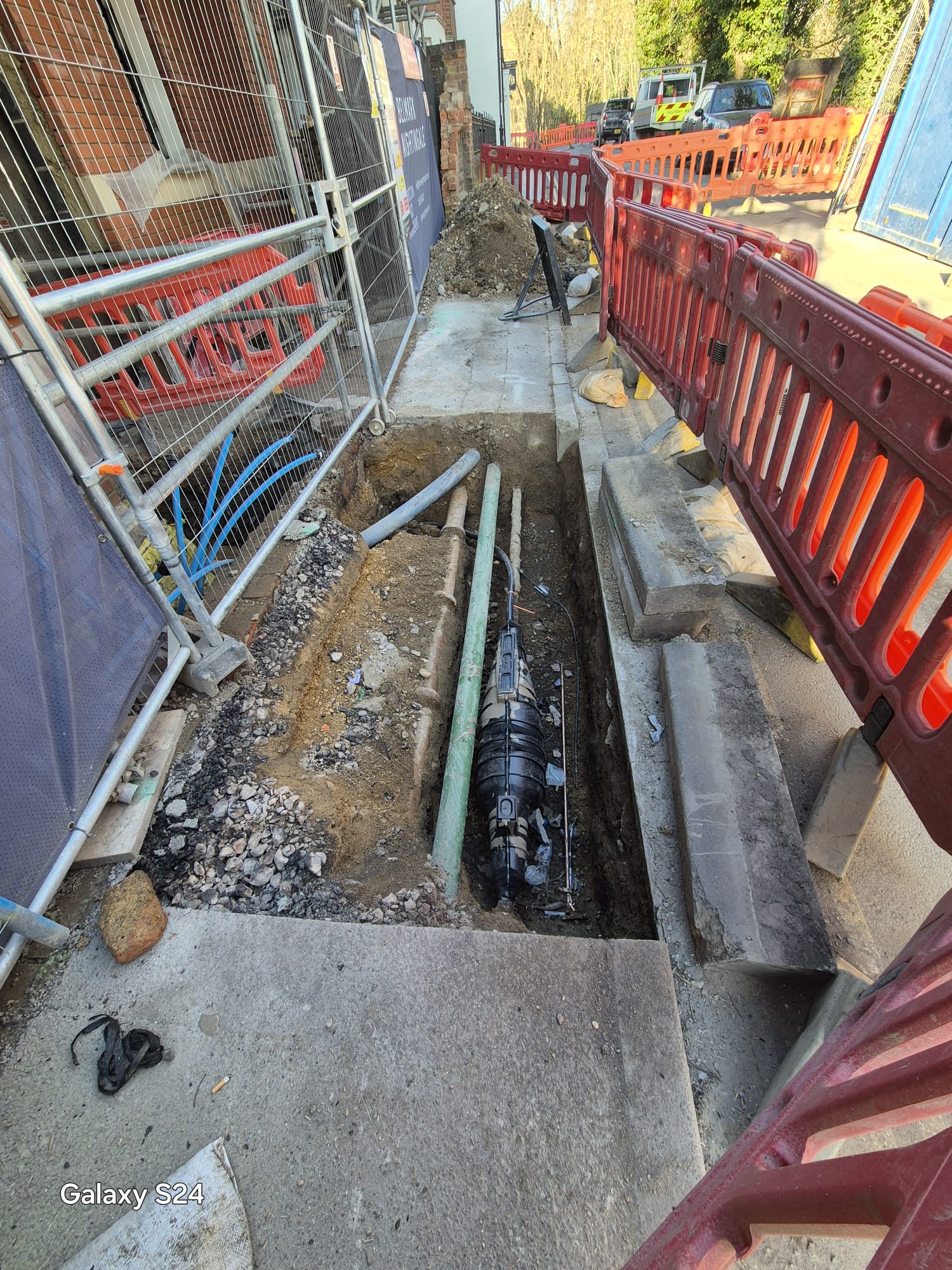 Utilities excavation guarded by barriers and fencing with a protected pedestrian route
